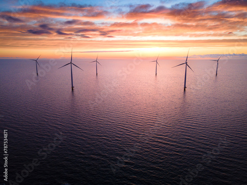 Sunset illuminating wind turbines in ocean, creating stunning natural landscape