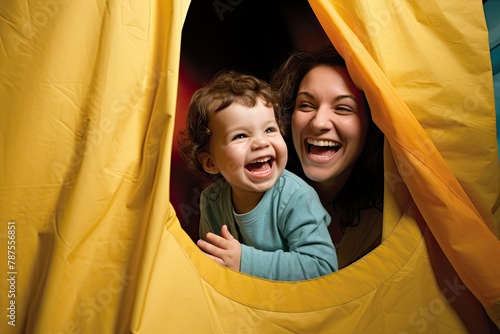 A woman holds a child inside a yellow tent. parents and kids play time concept. Generative AI