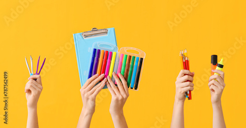 Many hands with school supplies on color background