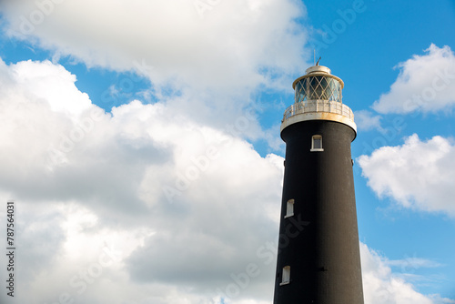 Historic disused lighthouse, which is still highly maintained for tourists and visitors, the tall black light house can be seen with a beautiful background of blue sky and cloud