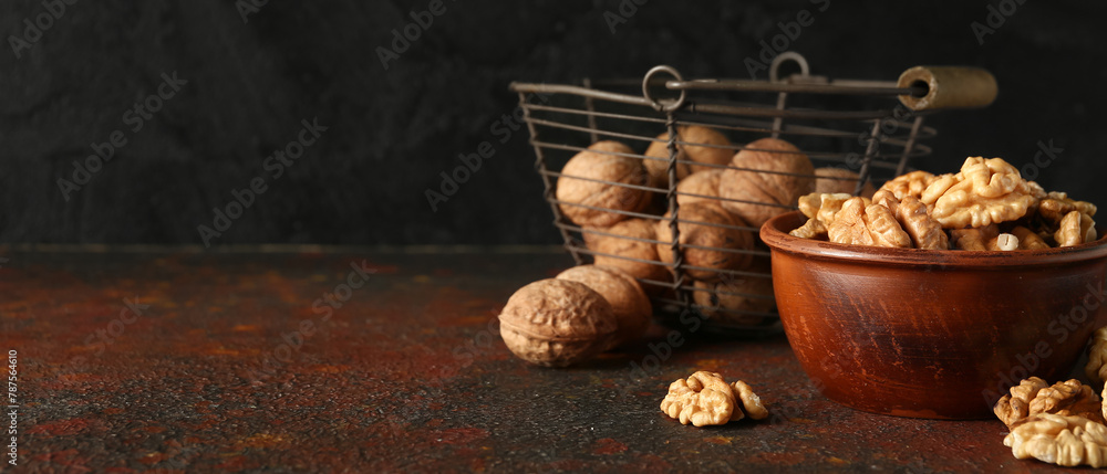Bowl and basket of tasty walnuts on table against black wall Bowl and basket of tasty walnuts on table against black wall