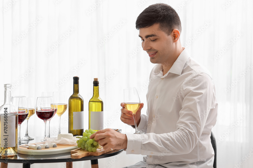 Young sommelier with glass of wine and grapes in kitchen Young sommelier with glass of wine and grapes in kitchen