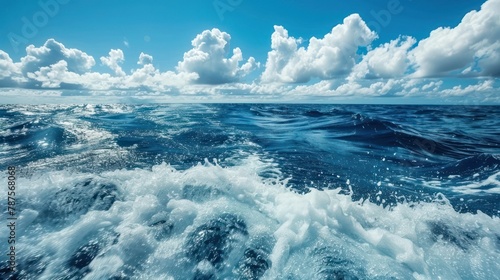 Beautiful sea waves surface with rolling and splashing foamy on white cloudy blue sky background.