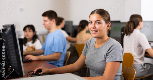 Positive young woman studying computer science in computer class. Woman learning to code.