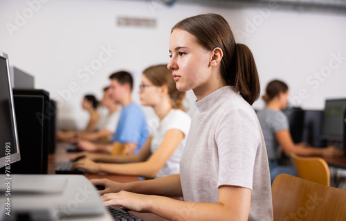 Teenage caucasian girl learning to use personal computer during lesson in school.