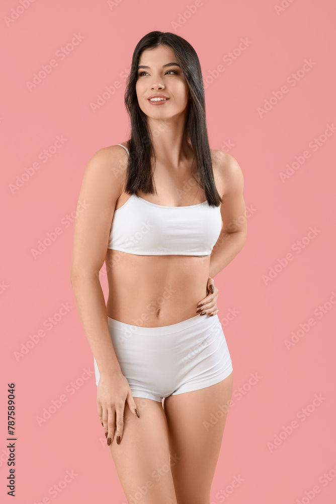 Fototapeta premium Beautiful young woman in white underwear on pink background