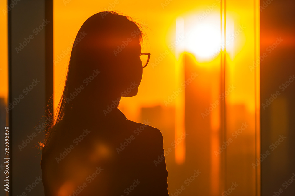 Young businesswoman looking through window of his office, bright future. Sunset light Young businesswoman looking through window of his office, bright future. Sunset light