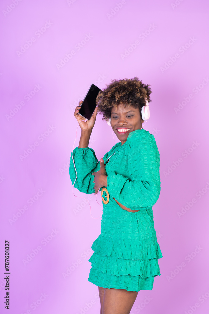 A woman in a green dress is holding a cell phone and wearing headphones A woman in a green dress is holding a cell phone and wearing headphones