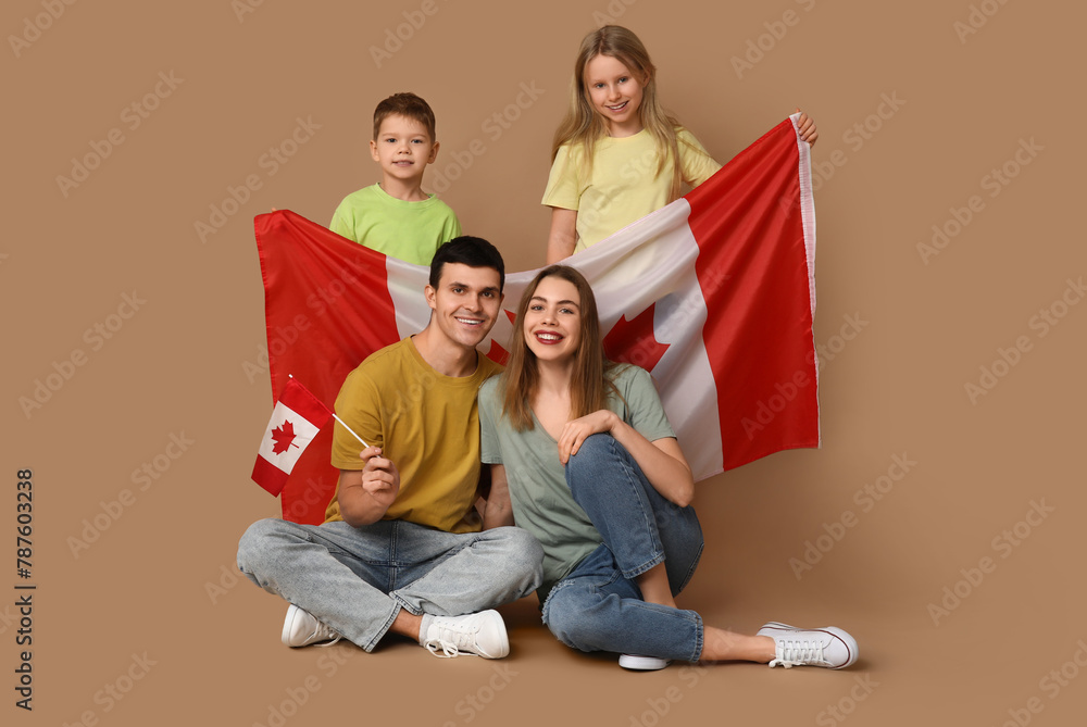 Happy family with flags of Canada sitting on brown background Happy family with flags of Canada sitting on brown background