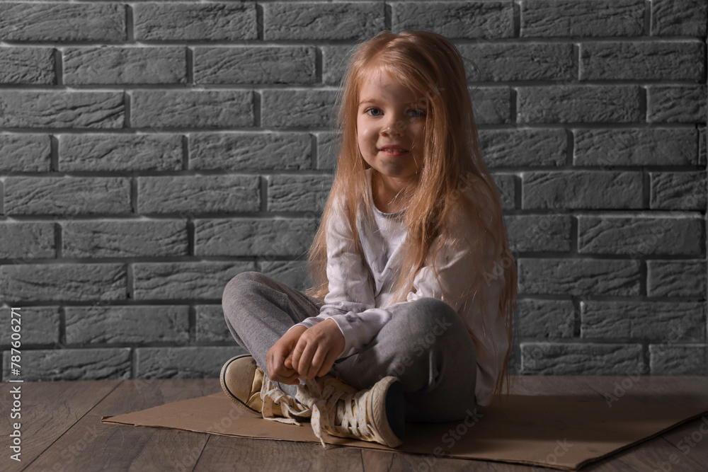Homeless little girl sitting near grey brick wall Homeless little girl sitting near grey brick wall