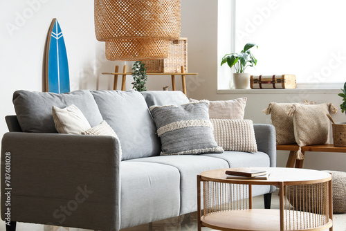 Beautiful interior of light living room with comfortable sofa, table, carpet and lamp © Pixel-Shot