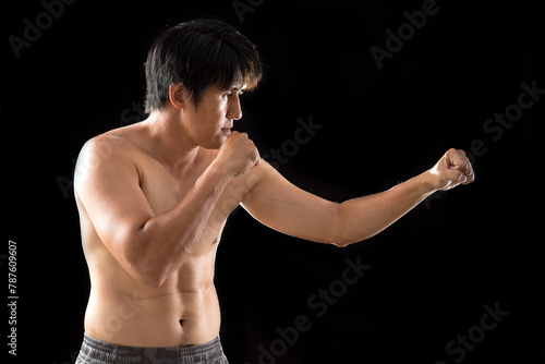 In the midst of martial arts practice against a black background, a young, fit Asian man delivers a perfect punch with precision and strength