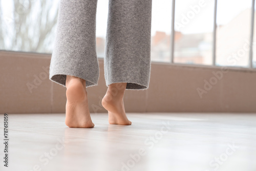 Woman walking on laminate floor at home, back view