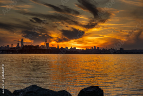 San Francisco Bay at sunset. 
The waters of the bay reflect hues of the sunset, in the distance, the cityscape of San Francisco, California.