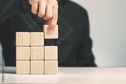 Hand putting and stacking blank wooden cubes on table with copy space for input wording or infographic icon
