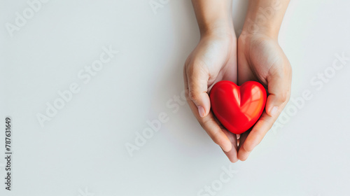 Cupped Hands Gently Holding a Glossy Red Heart, Symbolizing Care and Compassion on a Neutral Background