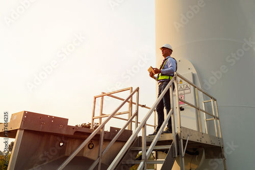 Senior maintenance engineer holding tablet working in wind turbine farm. Generator station, renewable energy