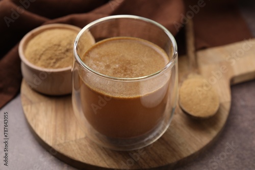 Soluble fiber with water in glass, powder and spoon on brown table, closeup