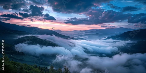 The sky is a beautiful mix of pink and blue hues, with clouds covering the mountains in the distance. The misty atmosphere adds a sense of mystery and tranquility to the scene