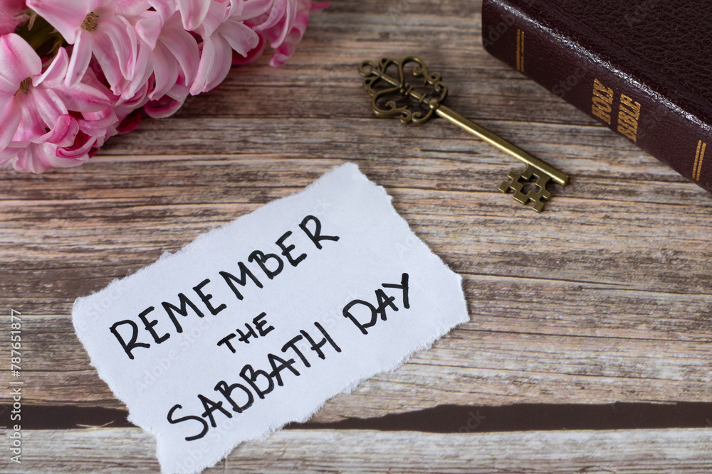 Naklejka premium Remember the Sabbath Day, handwritten note with holy bible, ancient key, and spring flower on wooden table. Christian obedience, keeping the commandments, rest for the people of God, biblical concept.