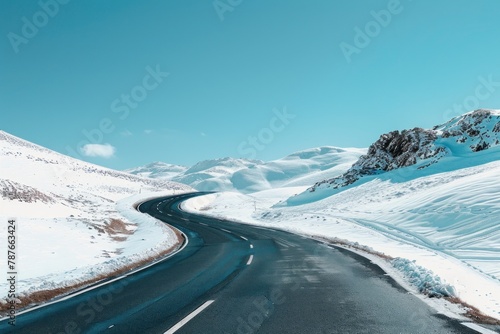 Winding road through snow-covered mountains under a clear blue sky.