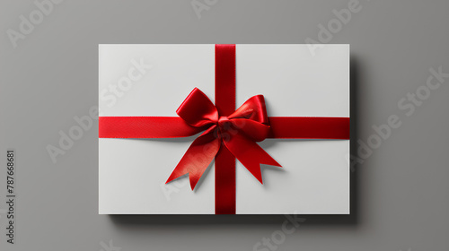 Blank white gift card with red ribbon bow isolated on grey background with shadow minimal conceptual © suldev