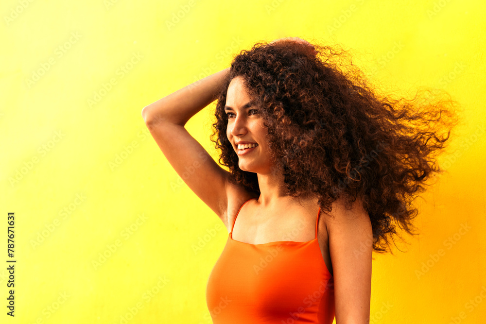 beautiful afro woman looking aside portrait leaning on a yellow wall. side view beautiful afro woman looking aside portrait leaning on a yellow wall. side view