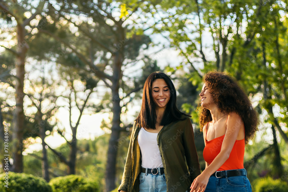 two young women couple walking in a park two young women couple walking in a park