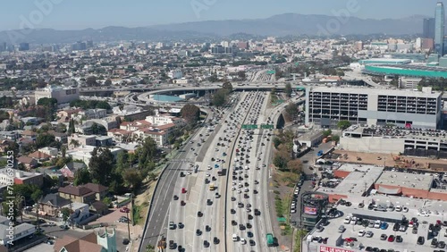 Aerial pullback view of busy freeway highway traffic and cars and garages