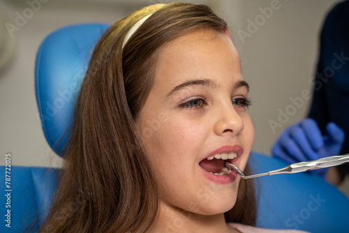 Closeup of cute little girl at dentist, open mouth , dentist looking her mouth with mirror tool 