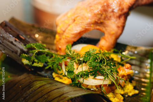 hand of an elderly woman preparing the ingredients of a Colombian tamale on some banana leaves photo
