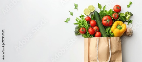 Healthy food delivery concept. Vegan and vegetarian food in a paper bag filled with fresh vegetables and fruits on a white background, with space for text.