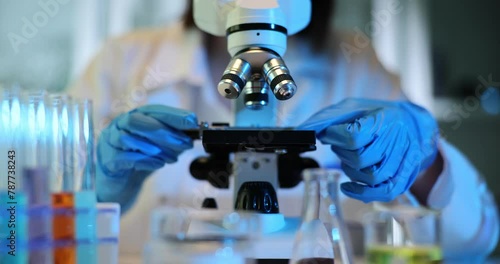 Researcher places sample under microscope in laboratory