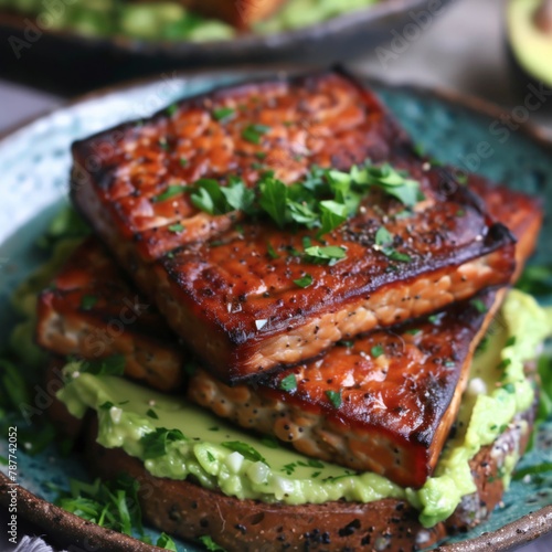 Gourmet tempeh steaks on avocado toast garnished with fresh parsley.