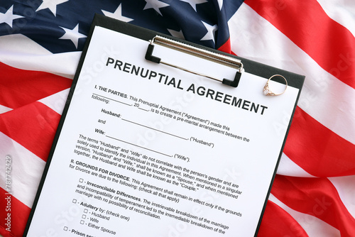 Prenuptial agreement and wedding ring on table. Premarital paperwork process in USA close up photo