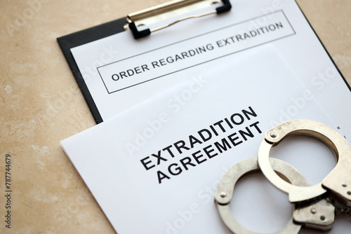 Extradition Agreement and Order Regarding Extradition with handcuffs on table close up