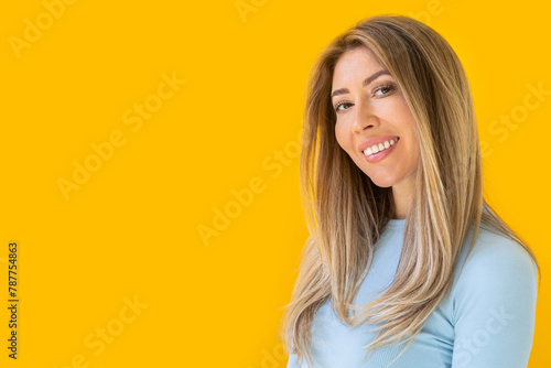 Portrait of a young Caucasian woman with pleasant smile isolated on yellow wall with copy space. 