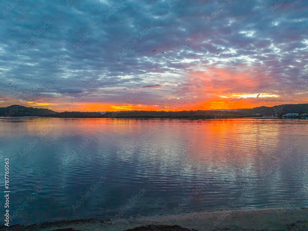 Sunrise over the bay water with clouds and birds in the sky Sunrise over the bay water with clouds and birds in the sky