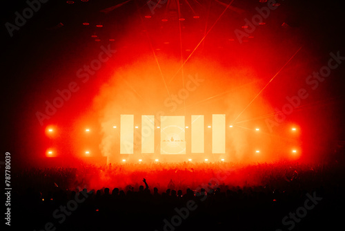 DJ performing infront of a large crowd with a large production of lasers and lights