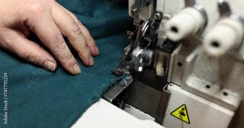 Seamstress uses overlock machine to secure fabric edges photo