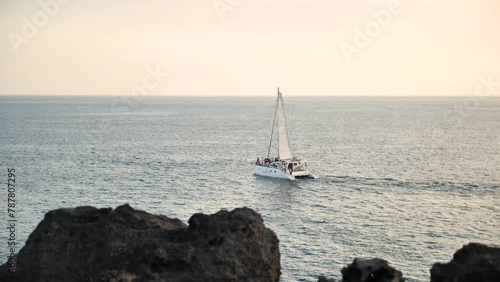 Sailing Yacht near Jusangjeollidae or Daepo Jusangjeolli Cliff at sunset in Jeju Island, Republic of Korea. Volcanic rock formation, columnar basalt cliffs along the coast in South Korea. photo