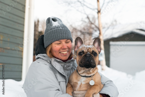 winter portrait of woman hugging french bulldog at snow place. Human and dog friendship.