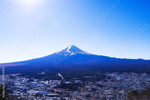 Look pass village and city at Mount Fuji world famous tourist attractions. Beautiful mountain with snow and white fog cover on top with bright blue sky, bright is background. © Thepporn