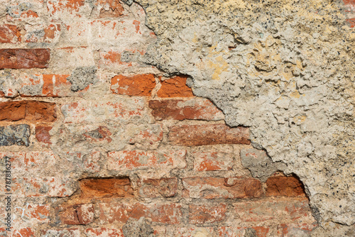 Fragment of an ancient medieval brick wall partially covered with plaster. Background. Texture.