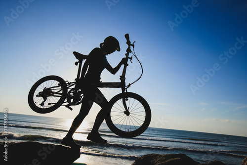 Woman taking a folding bike on sunrise seaside