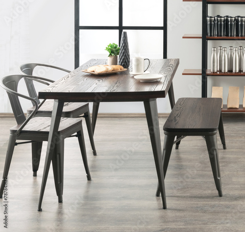 Casual morning dining scene in a contemporary space, with a textured dark wood table and bench, accented by an elegant industrial steel chair, all set for an energizing breakfast, lunch, dining scene photo