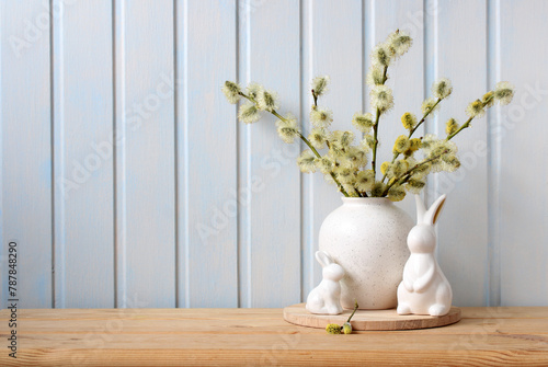 Easter bunny figurines and blooming fluffy willow branches on the table. Easter background, spring holiday backdrop. Copy space.