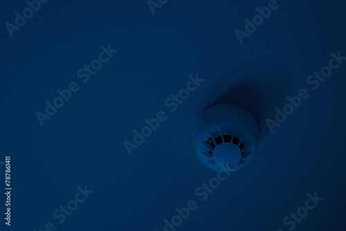 smoke detector mounted on plain ceiling at dark nighttime, fire alarm system, copy space