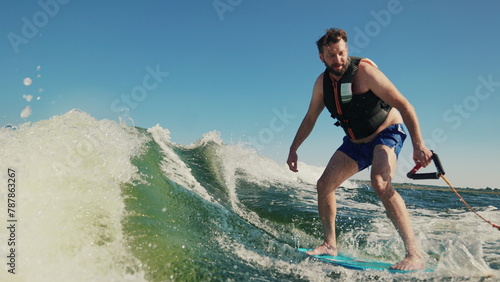 A man learns to wakesurf behind a boat. Fun on the water during the hot summer on the lake.