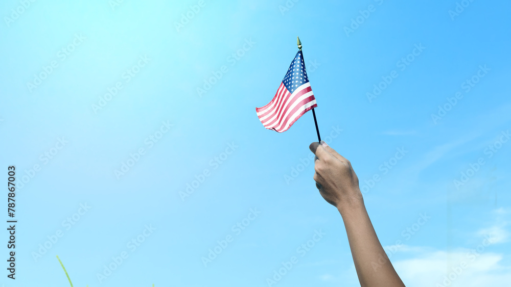 Closeup view of a human hand holding an American flag - obrazy, fototapety, plakaty 